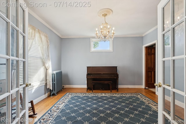 305 E 6th St, Monroe, MI 48161 - sitting room featuring radiator heating unit, wood finished floors, a chandelier, crown molding, and french doors