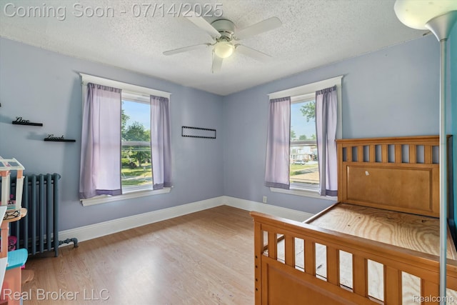 305 E 6th St, Monroe, MI 48161 - unfurnished bedroom with radiator, a textured ceiling, wood finished floors, and a ceiling fan