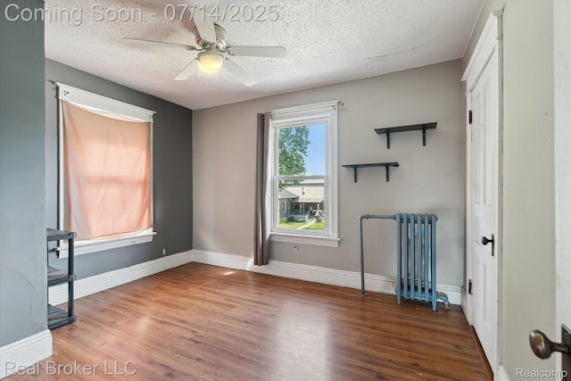 305 E 6th St, Monroe, MI 48161 - empty room featuring ceiling fan, a textured ceiling, radiator heating unit, and wood finished floors