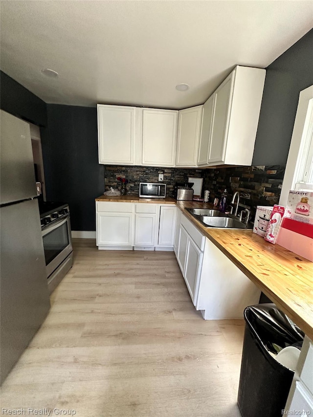 20245 Archdale St, Detroit, MI 48235 - kitchen with wood counters, appliances with stainless steel finishes, white cabinets, light wood-style flooring, and decorative backsplash
