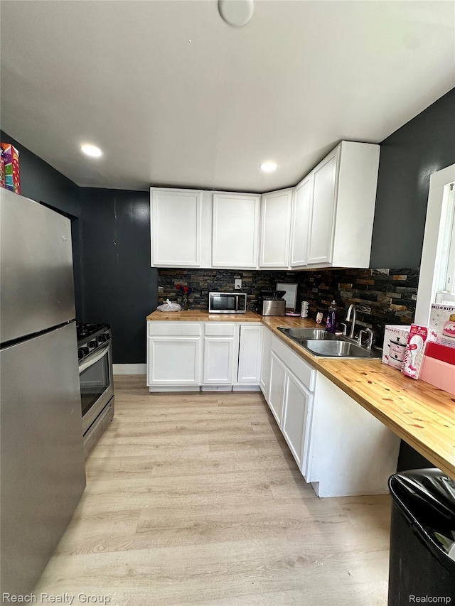 20245 Archdale St, Detroit, MI 48235 - kitchen with stainless steel appliances, butcher block counters, white cabinetry, tasteful backsplash, and light wood finished floors