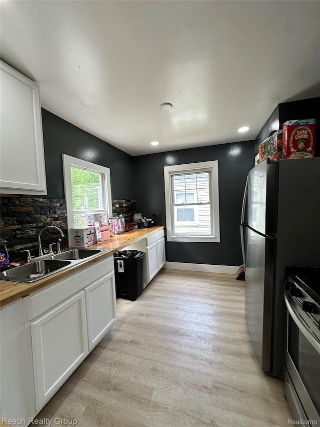 20245 Archdale St, Detroit, MI 48235 - kitchen with stainless steel range oven, white cabinets, light wood-type flooring, backsplash, and butcher block counters