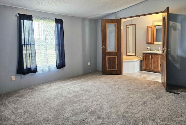 5955 N Pendell Rd, Elwell, MI 48832 - unfurnished bedroom with light carpet, a textured ceiling, vaulted ceiling, and ensuite bath