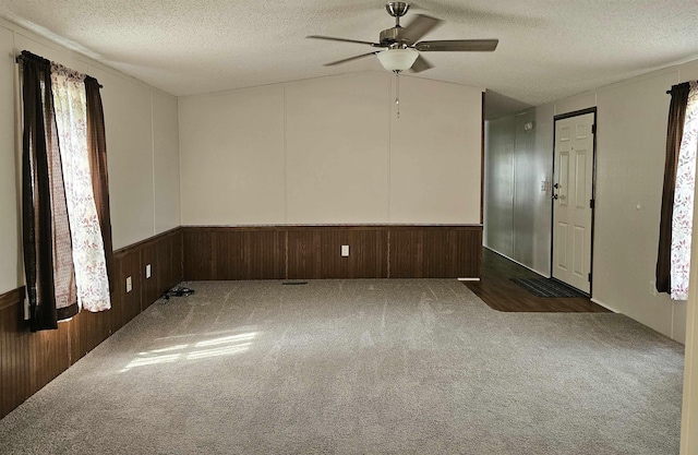 5955 N Pendell Rd, Elwell, MI 48832 - carpeted empty room with a textured ceiling, ceiling fan, vaulted ceiling, and wooden walls