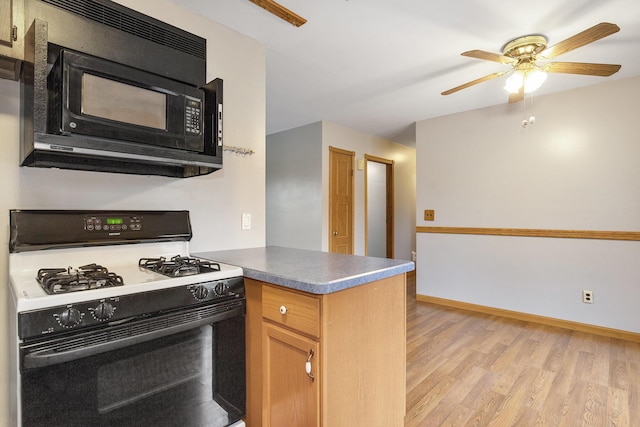 13280 Bradshaw St NE, Gowen, MI 49326 - kitchen with gas stove, black microwave, light wood-style floors, a peninsula, and ceiling fan