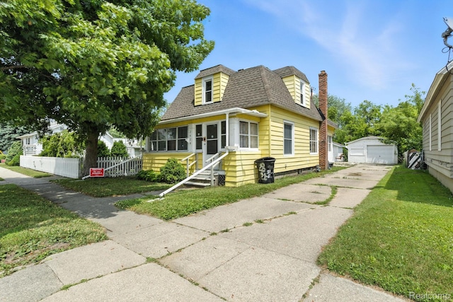 2424 10th Ave, Port Huron, MI 48060 - view of front of property featuring roof with shingles, a garage, an outbuilding, concrete driveway, and a chimney