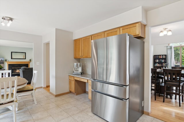 2388 Chestnut Cres, Saline, MI 48176 - kitchen with freestanding refrigerator, light stone counters, a warm lit fireplace, and light tile patterned floors