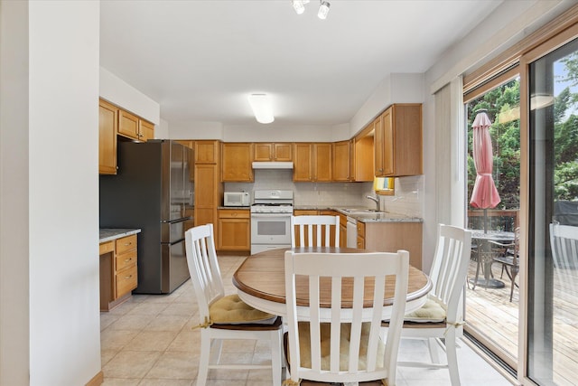2388 Chestnut Cres, Saline, MI 48176 - kitchen featuring white appliances, backsplash, under cabinet range hood, light tile patterned floors, and light stone counters
