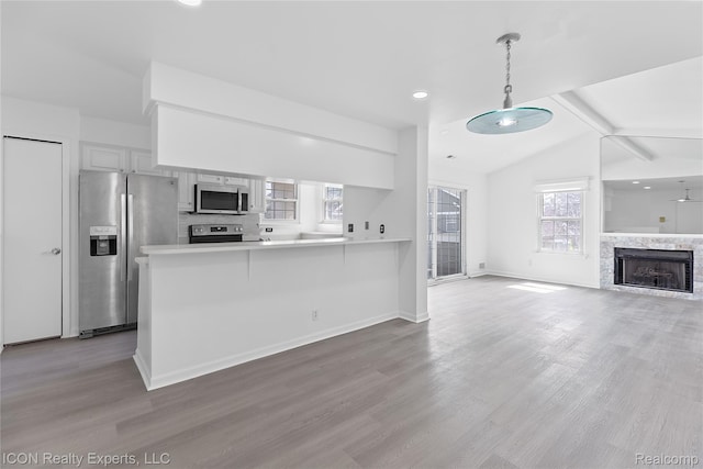 6614 Embers Ct, West Bloomfield, MI 48322 - kitchen with appliances with stainless steel finishes, light wood-type flooring, a peninsula, open floor plan, and decorative light fixtures