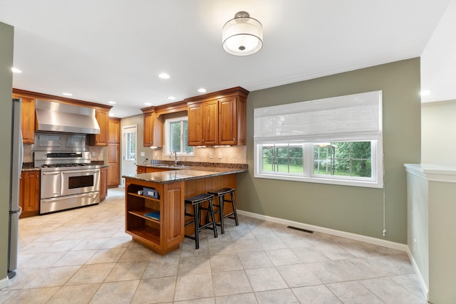 2113 Ridgeway Rd, Jackson, MI 49203 - kitchen with wall chimney exhaust hood, double oven range, a breakfast bar, tasteful backsplash, and recessed lighting