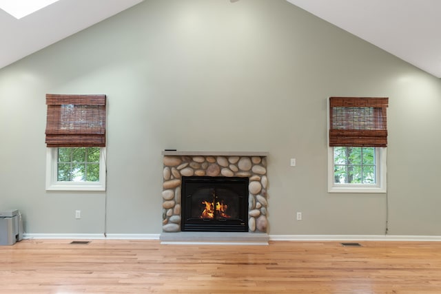 2113 Ridgeway Rd, Jackson, MI 49203 - unfurnished living room featuring high vaulted ceiling, wood finished floors, a stone fireplace, and healthy amount of natural light