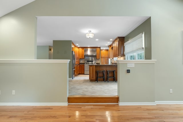 2113 Ridgeway Rd, Jackson, MI 49203 - kitchen featuring stainless steel appliances, a kitchen breakfast bar, brown cabinetry, light wood-type flooring, and recessed lighting