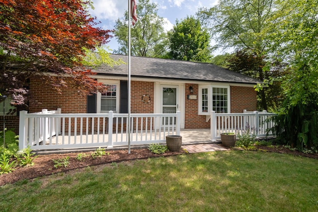 2113 Ridgeway Rd, Jackson, MI 49203 - view of front of home with brick siding, a front lawn, a shingled roof, and a deck