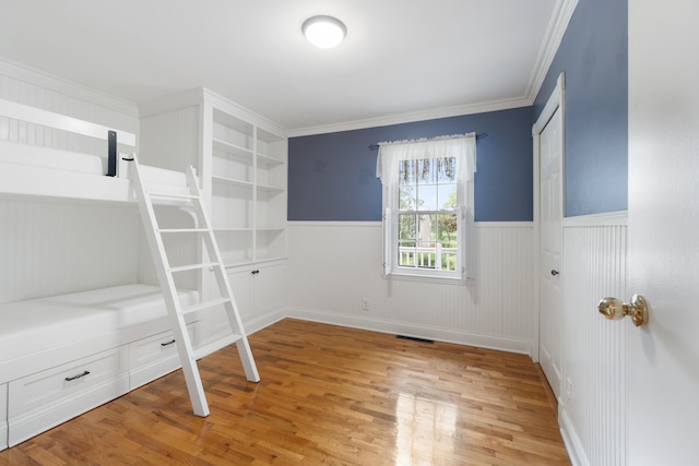 2113 Ridgeway Rd, Jackson, MI 49203 - unfurnished bedroom with a wainscoted wall, light wood-type flooring, and crown molding