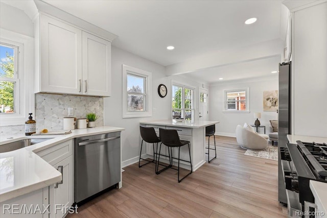 29924 Taylor St, Saint Clair Shores, MI 48082 - kitchen featuring dishwasher, a breakfast bar area, decorative backsplash, light wood-style floors, and white cabinets