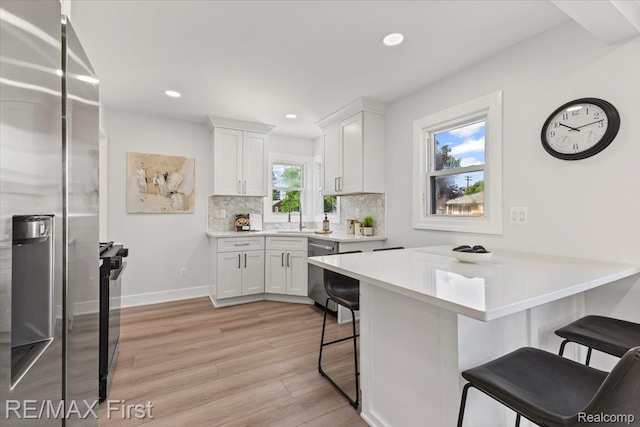 29924 Taylor St, Saint Clair Shores, MI 48082 - kitchen featuring appliances with stainless steel finishes, a kitchen bar, light wood-style floors, white cabinetry, and light countertops