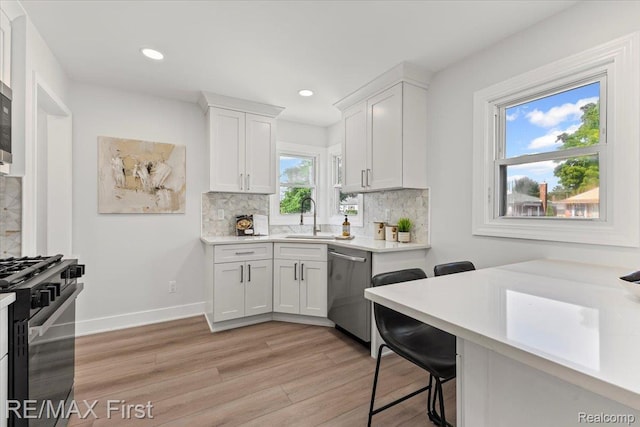 29924 Taylor St, Saint Clair Shores, MI 48082 - kitchen with black gas range oven, stainless steel dishwasher, light wood-type flooring, light countertops, and backsplash