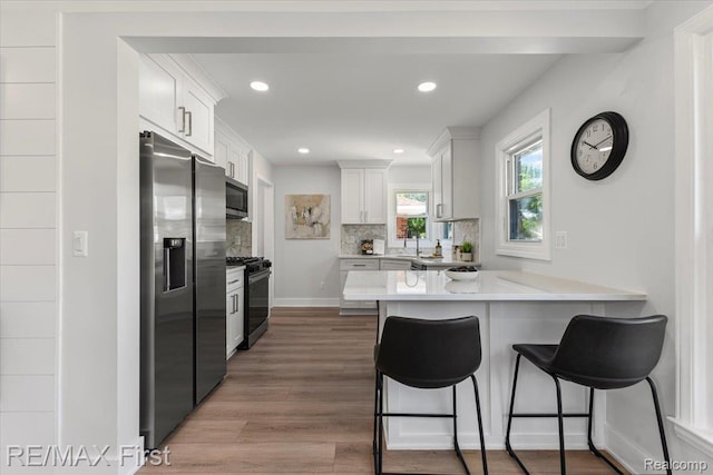 29924 Taylor St, Saint Clair Shores, MI 48082 - kitchen featuring appliances with stainless steel finishes, a peninsula, backsplash, a breakfast bar area, and recessed lighting