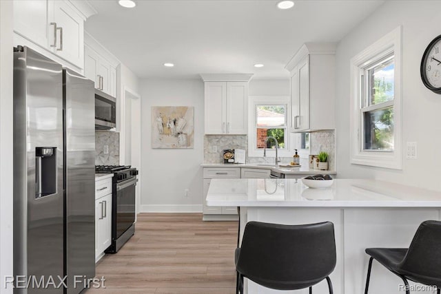 29924 Taylor St, Saint Clair Shores, MI 48082 - kitchen with stainless steel appliances, a peninsula, backsplash, light countertops, and light wood-style flooring
