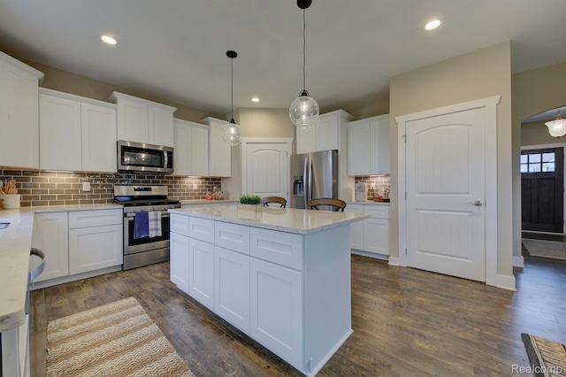 MOH45 Birkdale Dr Unit 45, Howell, MI 48843 - kitchen featuring appliances with stainless steel finishes, a kitchen island, dark wood-style flooring, tasteful backsplash, and white cabinets