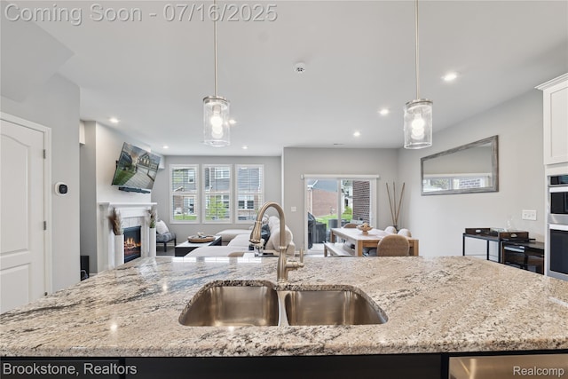 765 Hummingbird Dr, Rochester Hills, MI 48307 - kitchen featuring open floor plan, recessed lighting, pendant lighting, light stone countertops, and a warm lit fireplace