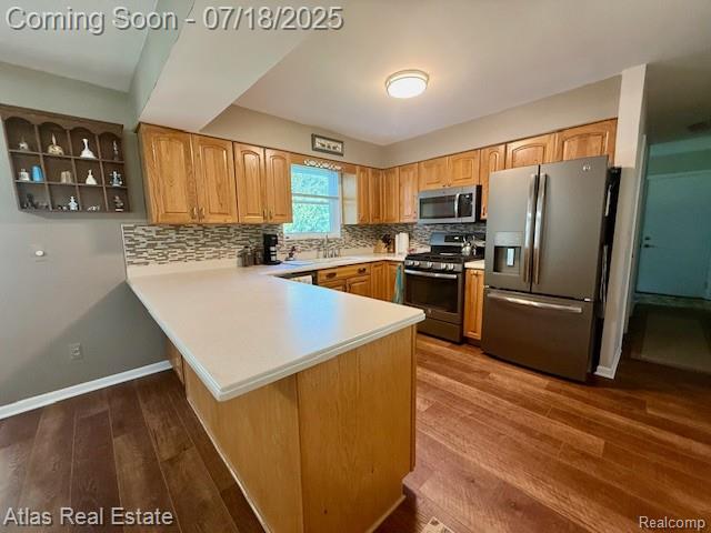8354 Ridge Rd, Goodrich, MI 48438 - kitchen featuring stainless steel appliances, a peninsula, dark wood-style flooring, light countertops, and backsplash