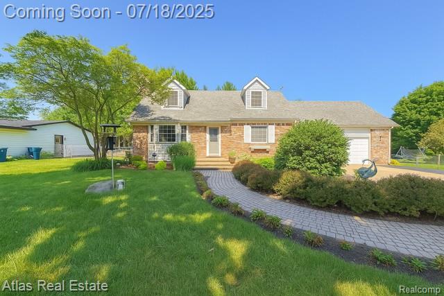 8354 Ridge Rd, Goodrich, MI 48438 - cape cod-style house featuring a garage, a front yard, and brick siding