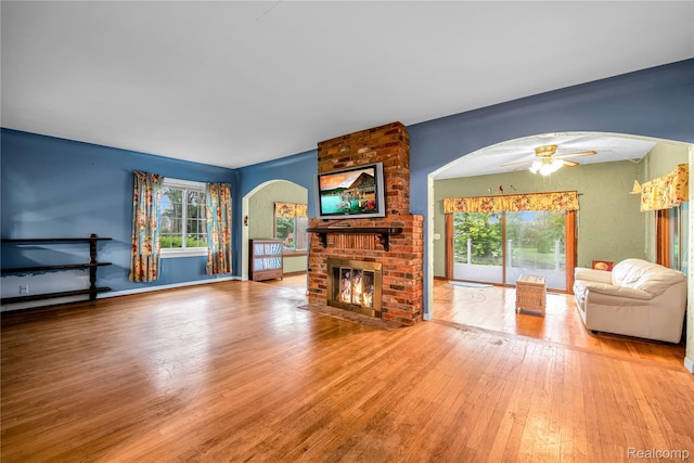 3870 Benstein Rd, Commerce Twp, MI 48382 - living area featuring arched walkways, a brick fireplace, hardwood / wood-style floors, and a ceiling fan