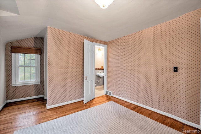 3870 Benstein Rd, Commerce Twp, MI 48382 - additional living space featuring wood finished floors, wallpapered walls, and lofted ceiling
