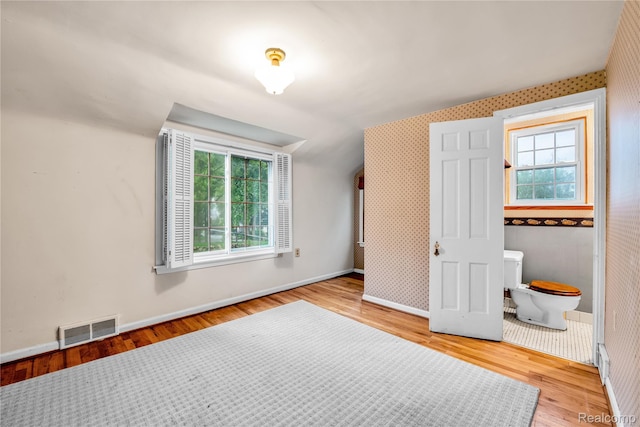 3870 Benstein Rd, Commerce Twp, MI 48382 - unfurnished bedroom featuring wood finished floors and multiple windows