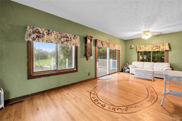 3870 Benstein Rd, Commerce Twp, MI 48382 - living area featuring wood finished floors, healthy amount of natural light, a ceiling fan, and a textured wall