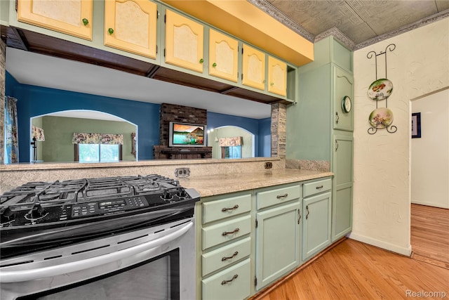 3870 Benstein Rd, Commerce Twp, MI 48382 - kitchen featuring stainless steel gas stove, green cabinetry, light wood-style floors, light countertops, and an ornate ceiling