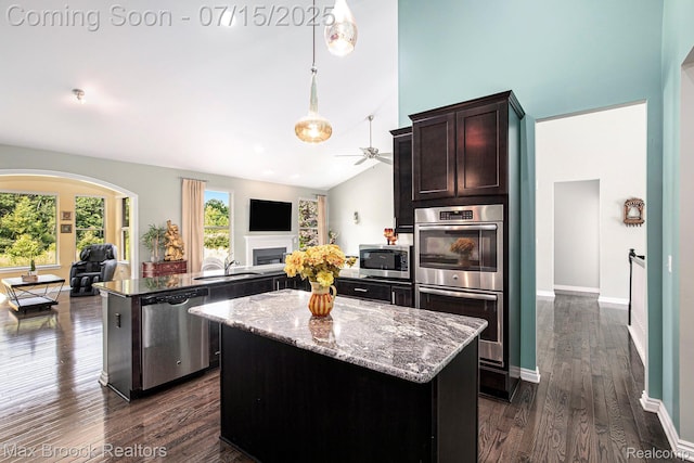 23395 Stoneleigh Ct, South Lyon, MI 48178 - kitchen featuring appliances with stainless steel finishes, open floor plan, a kitchen island, a fireplace, and ceiling fan