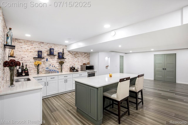 23395 Stoneleigh Ct, South Lyon, MI 48178 - kitchen featuring stainless steel microwave, white cabinets, light countertops, a kitchen breakfast bar, and light wood-style floors