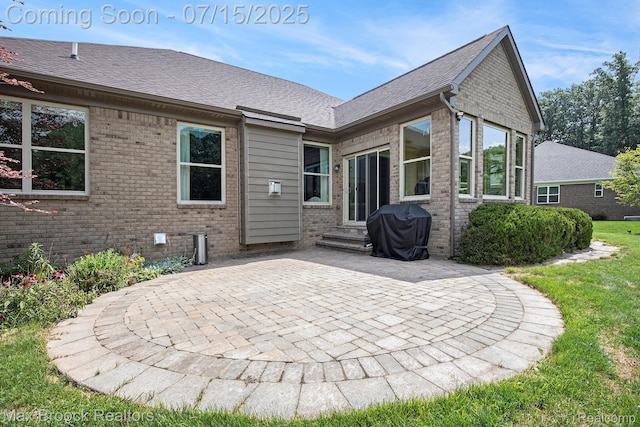 23395 Stoneleigh Ct, South Lyon, MI 48178 - rear view of house featuring a patio area, brick siding, roof with shingles, and a yard