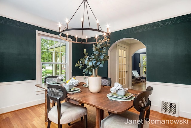 1055 San Lucia Dr SE, Grand Rapids, MI 49506 - dining space with arched walkways, light wood finished floors, a chandelier, and ornamental molding