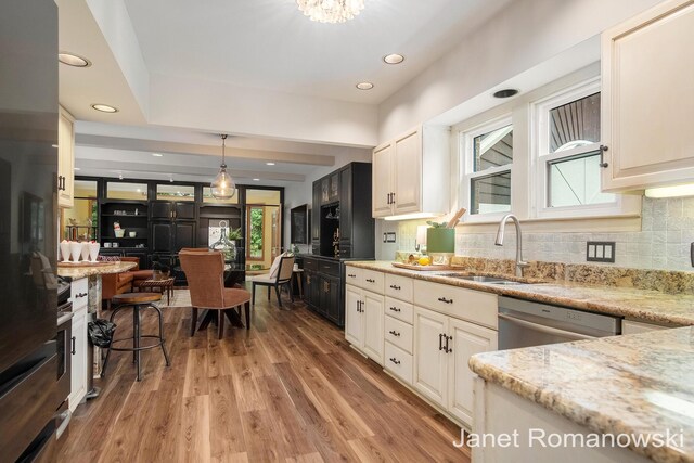 1055 San Lucia Dr SE, Grand Rapids, MI 49506 - kitchen featuring stainless steel dishwasher, light stone countertops, light wood-style flooring, decorative backsplash, and recessed lighting
