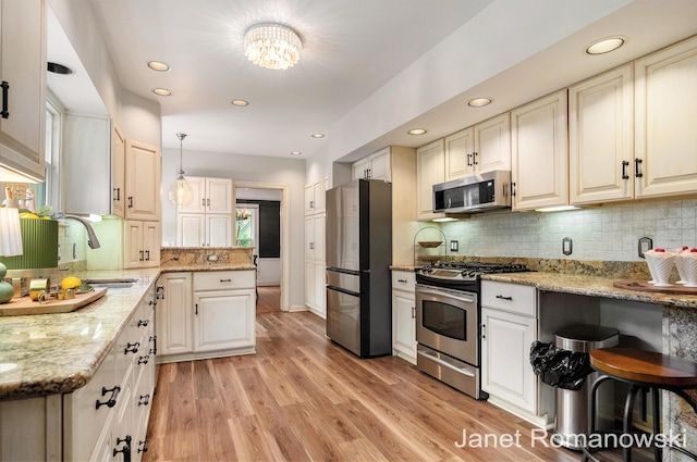 1055 San Lucia Dr SE, Grand Rapids, MI 49506 - kitchen with stainless steel appliances, tasteful backsplash, light stone counters, light wood-type flooring, and recessed lighting