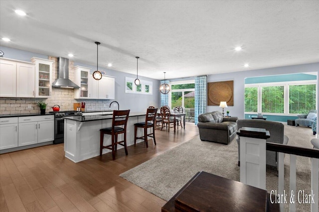 4454 Keena Ct NE Unit 71, Grand Rapids, MI 49525 - kitchen with stainless steel range with gas cooktop, wall chimney exhaust hood, open floor plan, a kitchen bar, and recessed lighting