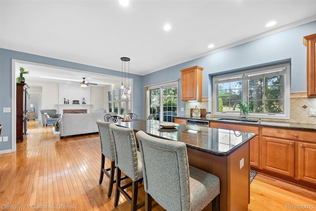 1760 Bedlington Ct, Rochester Hills, MI 48307 - kitchen featuring a kitchen island, a breakfast bar, stainless steel dishwasher, light wood-style floors, and ornamental molding