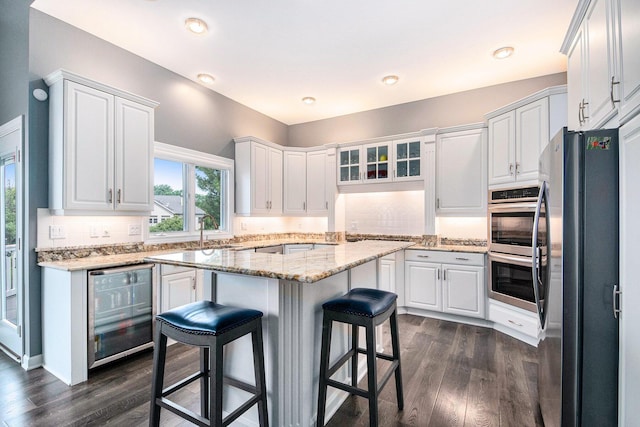 172 Bay Meadows Dr, Holland, MI 49424 - kitchen with wine cooler, appliances with stainless steel finishes, dark wood-type flooring, a kitchen bar, and recessed lighting