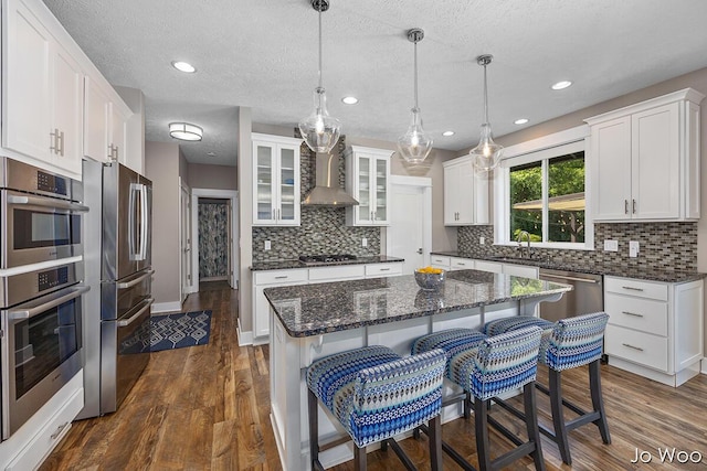 5362 Settlers Grove Rd NE, Belmont, MI 49306 - kitchen with stainless steel appliances, wall chimney range hood, dark wood-style floors, white cabinetry, and backsplash