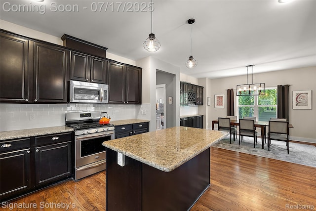 1120 Wyandotte Ave, Royal Oak, MI 48067 - kitchen featuring appliances with stainless steel finishes, dark wood-style flooring, decorative backsplash, hanging light fixtures, and light stone countertops