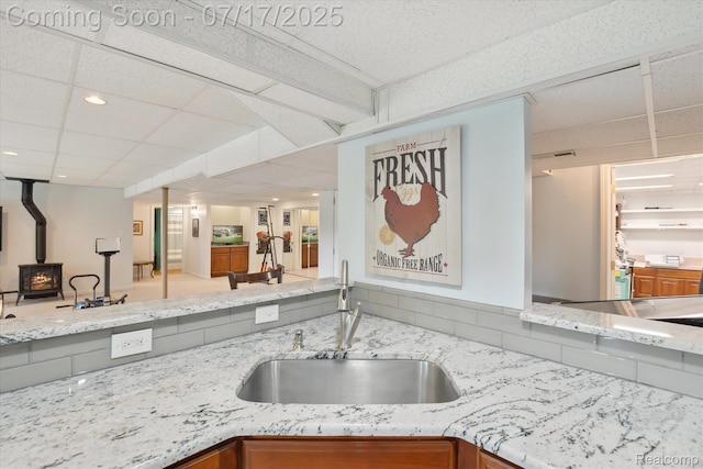 1847 Brandy Ln, Brighton, MI 48114 - kitchen featuring a wood stove, open floor plan, a paneled ceiling, light stone countertops, and brown cabinetry