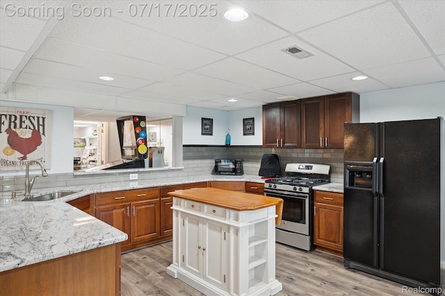 1847 Brandy Ln, Brighton, MI 48114 - kitchen featuring black refrigerator with ice dispenser, gas stove, light wood-style flooring, a paneled ceiling, and backsplash