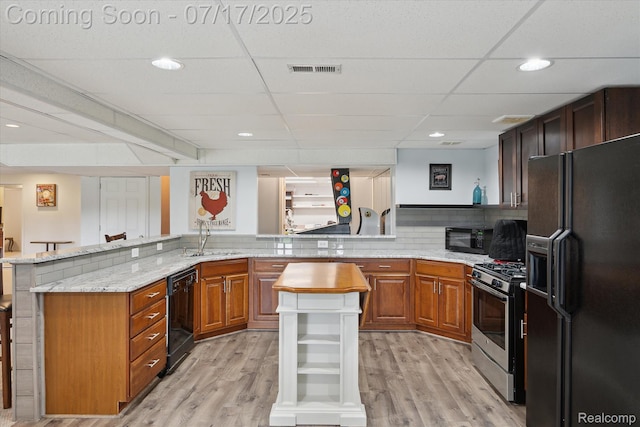 1847 Brandy Ln, Brighton, MI 48114 - kitchen with black appliances, a peninsula, light wood finished floors, light stone counters, and recessed lighting