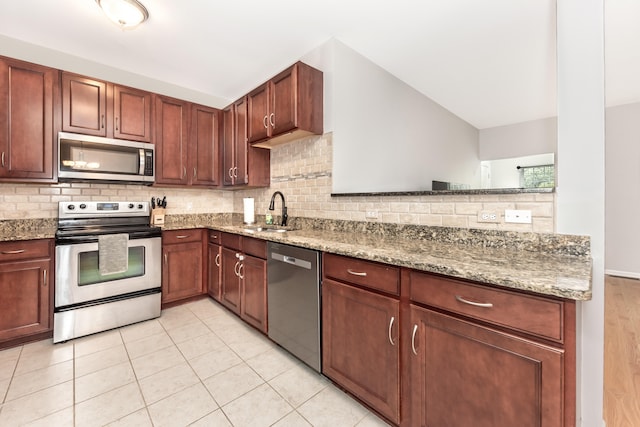 241 W Oakbrook Dr, Ann Arbor, MI 48103 - kitchen featuring stainless steel appliances, backsplash, light stone counters, light tile patterned floors, and a peninsula