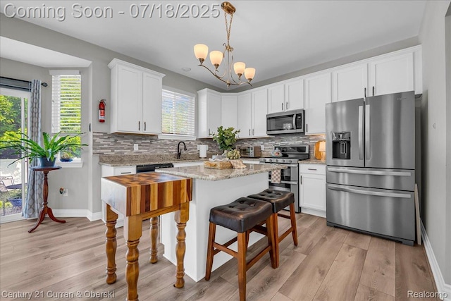 21150 Bryce Ct, Romulus, MI 48174 - kitchen with stainless steel appliances, light wood-style floors, white cabinetry, and a chandelier