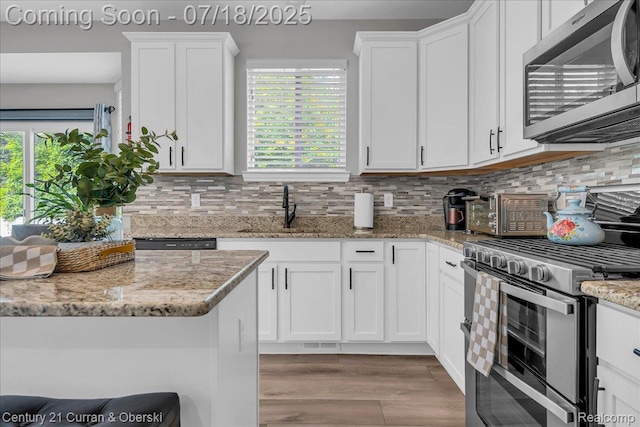 21150 Bryce Ct, Romulus, MI 48174 - kitchen featuring stainless steel appliances, white cabinets, wood finished floors, and backsplash