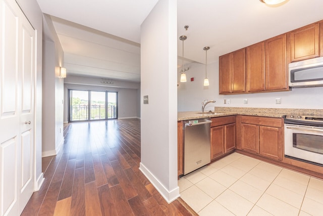 111 N Ashley St Unit 412, Ann Arbor, MI 48104 - kitchen featuring appliances with stainless steel finishes, brown cabinetry, light stone countertops, light wood-style flooring, and open floor plan